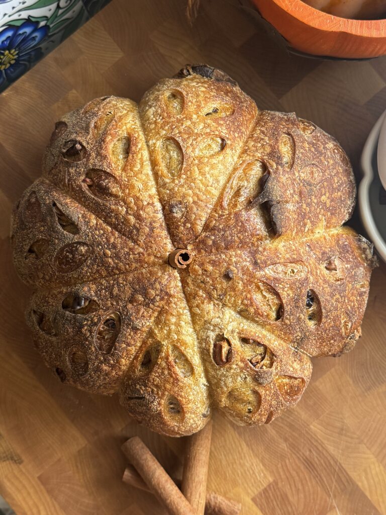 Baked loaf of pumpkin pecan sourdough bread on a cutting board